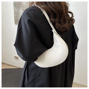 Détail du sac demi-lune blanc avec motif croco embossé porté à l'épaule pour femme
