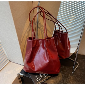 Detail of glossy burgundy tote bag with slender straps and soft reflective texture