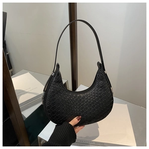 Détail du sac hobo en cuir tressé noir tenu à la main avec texture de luxe et bandoulière