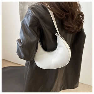 Close-up of a white crescent moon shoulder bag with textured finish and silver zipper detail