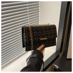 Detailed view of black and gold tweed texture with metallic chain and gold-tone clasp