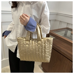 Detail of the golden quilted handbag showing vertical stitching and metallic texture