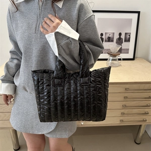 Fashionable black quilted puffer tote bag with vertical stitching for winter commuting
