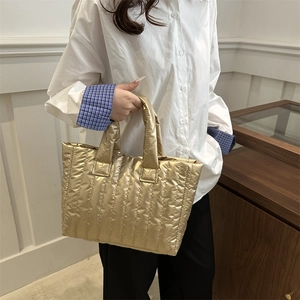 Golden quilted tote bag with metallic finish and vertical stitching for chic winter style