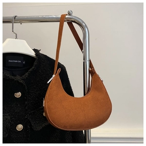 Detailed view of brown suede crescent bag with smooth matte texture and silver hardware