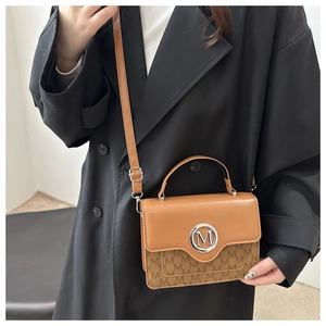 Close-up of vintage brown leather handbag with silver M logo and monogram pattern