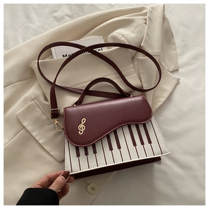 Dettaglio borsa bordeaux tema pianoforte con chiave di violino dorata e tastiera