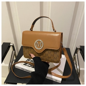 Détail du sac en cuir marron avec logo M métallique et motifs monogrammes élégants