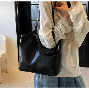 Spacious black tote bag worn on shoulder showing large capacity and minimalist style