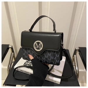 Détail du tissu jacquard à motif M gris et fermoir argenté sur sac carré noir