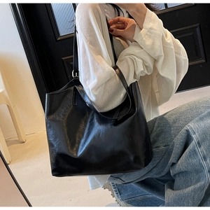 Close-up of a large black oil-wax leather tote bag showing soft texture and long straps