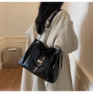 Vue latérale du sac bandoulière noir à chaîne avec fermoir doré porté par un mannequin