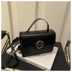 Détail du sac bandoulière noir avec logo 'M' en métal et texture à motif jacquard