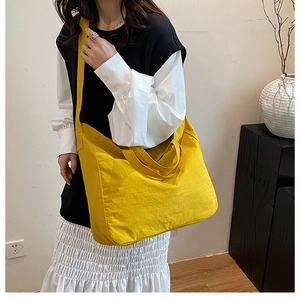Detailed view of spacious yellow tote bag featuring crinkle texture and wide shoulder strap
