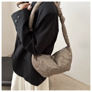 Détail d'un sac demi-lune matelassé à fleurs avec large bandoulière et fermeture éclair