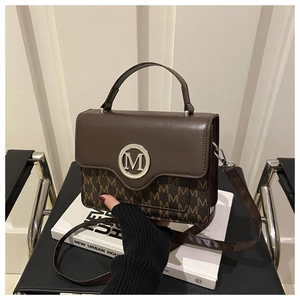 Détail d'un sac bandoulière marron avec monogramme et poignée en cuir sur une chaise