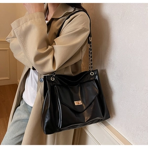 Détail du grand sac cabas noir avec bandoulière en chaîne dorée et fermoir rotatif