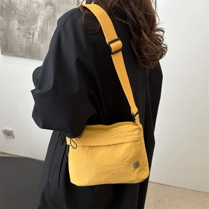 Minimalist bright yellow nylon crossbody bag with adjustable strap shown on model back