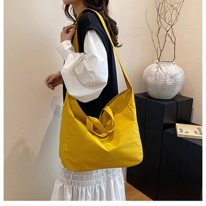 Lifestyle shot of a vibrant yellow large capacity tote bag worn by a model in a minimalist setting