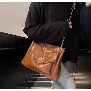Détail du sac fourre-tout marron en similicuir avec fermoir doré et bandoulière en chaîne