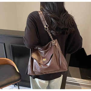 Détail du sac en cuir marron foncé avec fermoir doré et bandoulière en chaîne