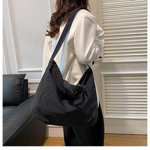 Detailed view of the large black tote bag worn by a model in a minimalist setting