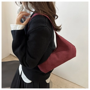 Macro detail of wine red suede shoulder bag showing frosted texture and trapezoid design