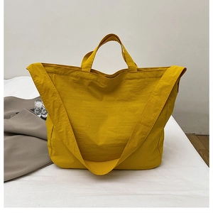 Detail of a bright yellow nylon tote bag with wide shoulder strap and double handles