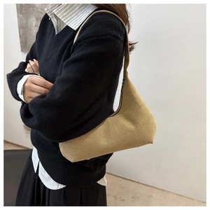 Detailed shot of mustard yellow suede hobo bag worn over the shoulder with wide strap