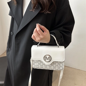 Sac bandoulière blanc avec imprimé M et logo argenté sur fond de trench-coat noir