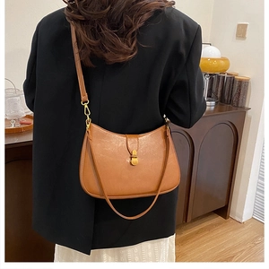 Detail of caramel leather hobo bag featuring vintage gold metal buckle and fine texture