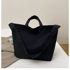 Detail of spacious black canvas tote bag with reinforced handles and wide shoulder straps