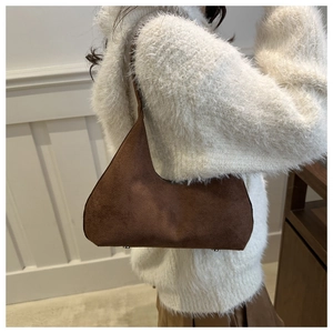 Detailed view of the bottom metal rivets on a high-quality dark brown suede shoulder bag