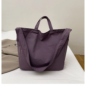 Detail view of purple nylon tote bag with dual straps on a soft neutral background