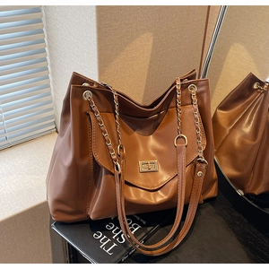 Détail d'un grand sac cabas marron avec bandoulière chaîne dorée et fermoir rotatif