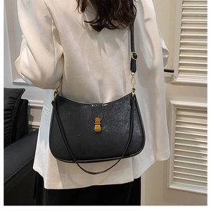 Close-up of black crescent bag featuring lychee texture and gold metal hardware