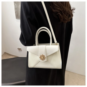 Close-up of white crossbody bag featuring vintage gold buckle and envelope flap detail