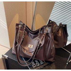 Détail du sac cabas marron foncé avec fermoir tournant doré et bandoulière en chaîne