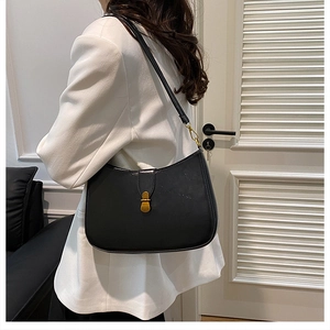 Detailed side view of black leather crescent underarm bag with gold metal buckle