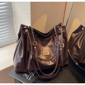 Détail du sac cabas marron foncé avec fermoir doré et bandoulière en chaîne