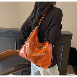 Grand cabas vintage en cuir orange avec double fermeture éclair porté par un mannequin
