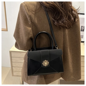 Detail of black leather crossbody bag with vintage gold floral lock on model back