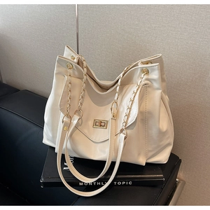 Détail du sac cabas beige avec cuir texturé, fermoir pivotant et bandoulière chaîne