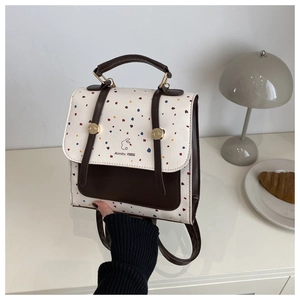 Detail of cream backpack with colorful polka dots, rabbit print, and gold clasp