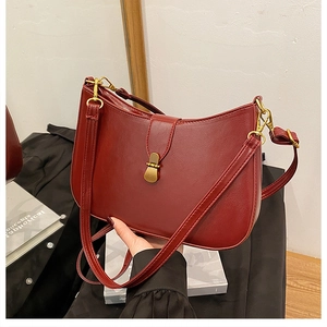 Close-up of vintage dark red crescent bag with polished gold metal buckle and leather texture