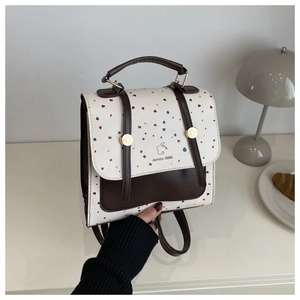 Detailed view of cream polka dot backpack with brown leather straps and vintage rabbit logo