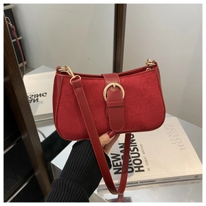 Close-up of red suede shoulder bag with golden metal ring buckle and slim leather strap