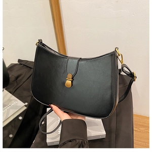 Detail of black crescent shoulder bag with vintage bronze metal buckle and leather texture