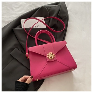 Detail of magenta envelope bag with a golden floral buckle on a dark grey blazer