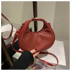 Close-up of red woven crescent bag featuring intricate texture and metal buckle
